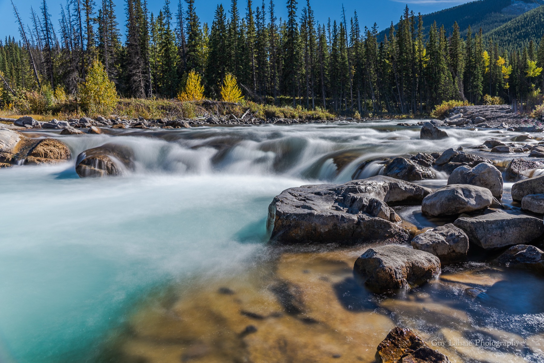 Rivière turquoise cascadant sur des rochers dans les Rocheuses canadiennes.